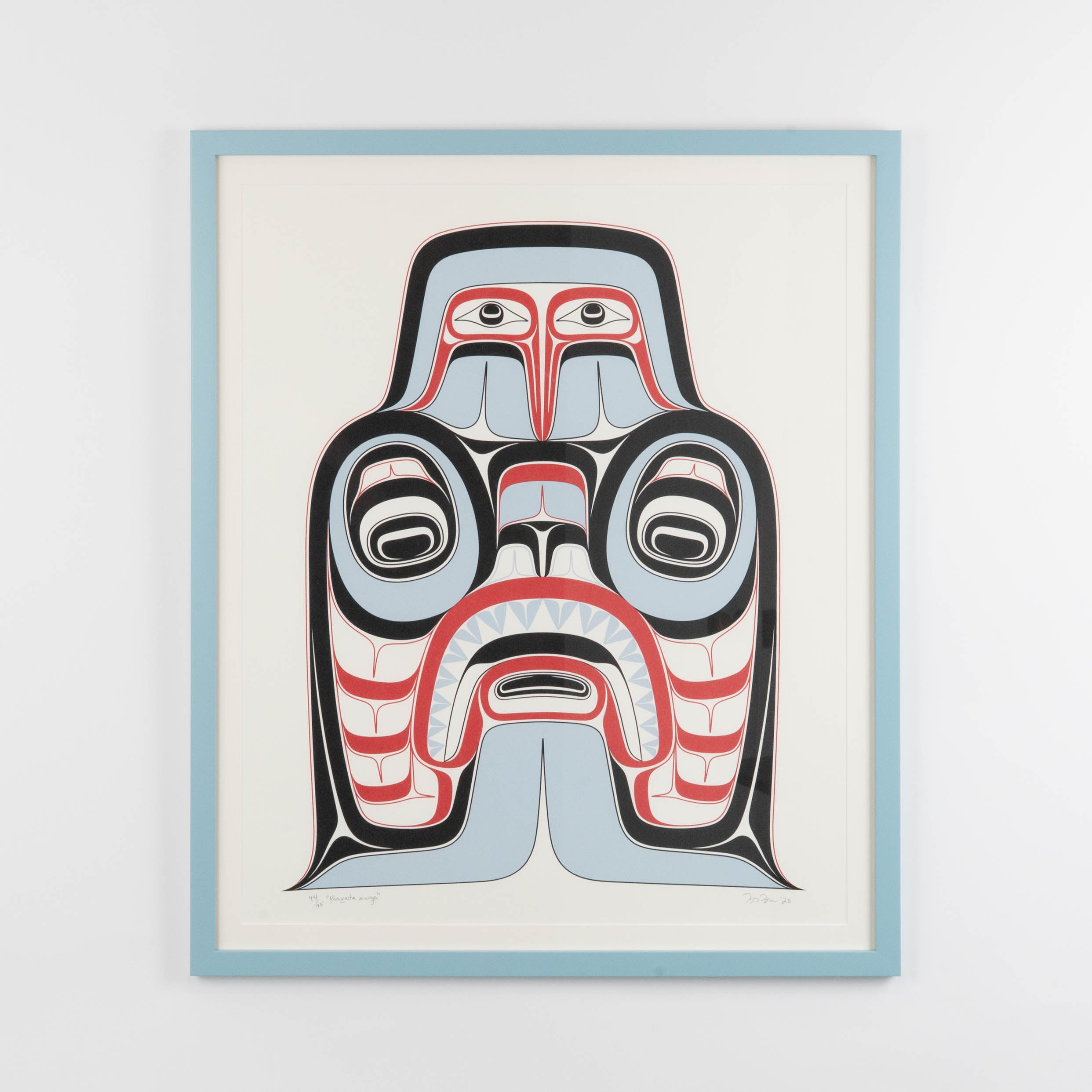 Haida Art print featuring a supernatural being, Dogfish mother. with bold red and black, and soft blue hues to show contrast, framed in a light blue frame.