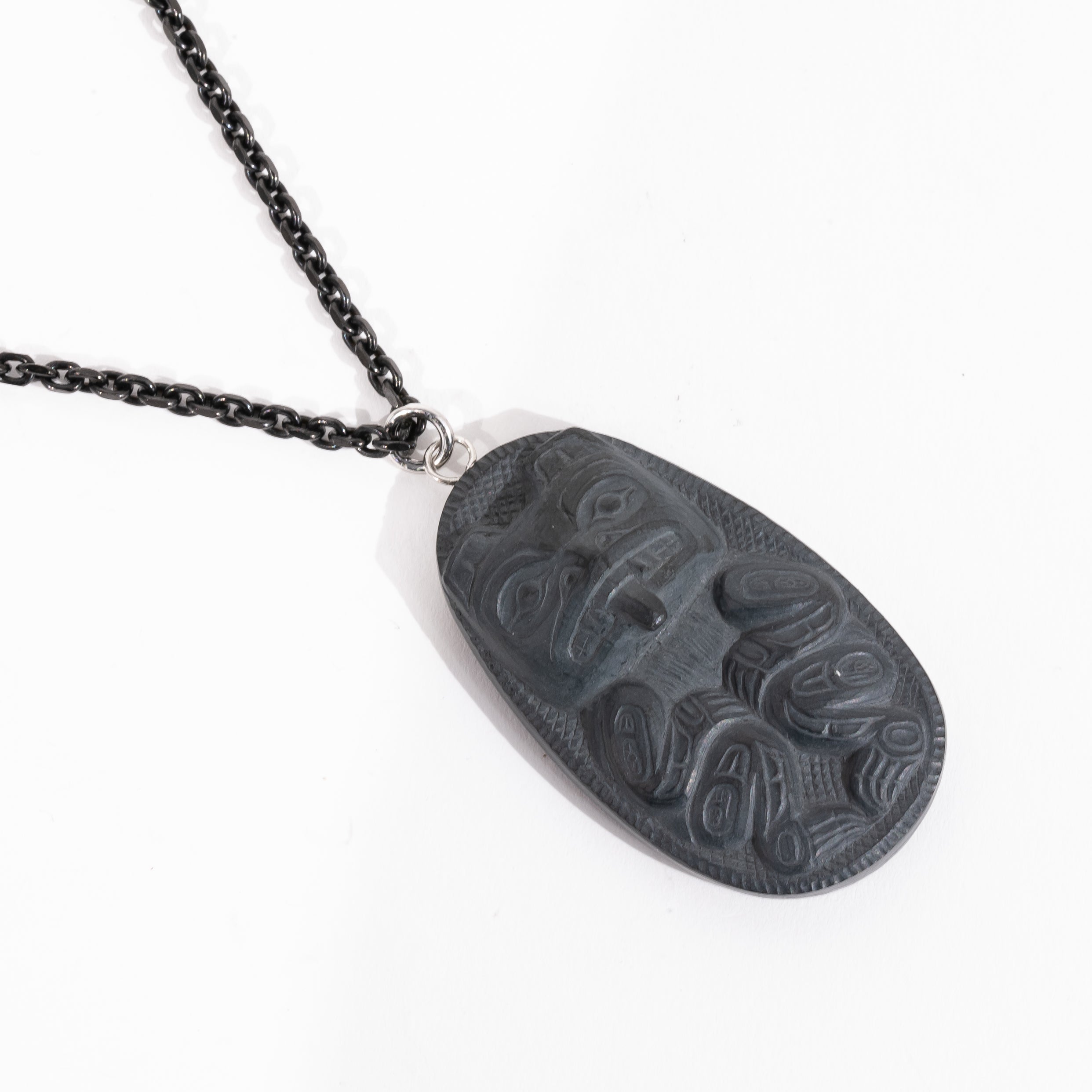Black Argillite Bear pendant necklace with intricate Haida Carvings on a white background made by Local Haida Gwaii Artist Melanie Russ