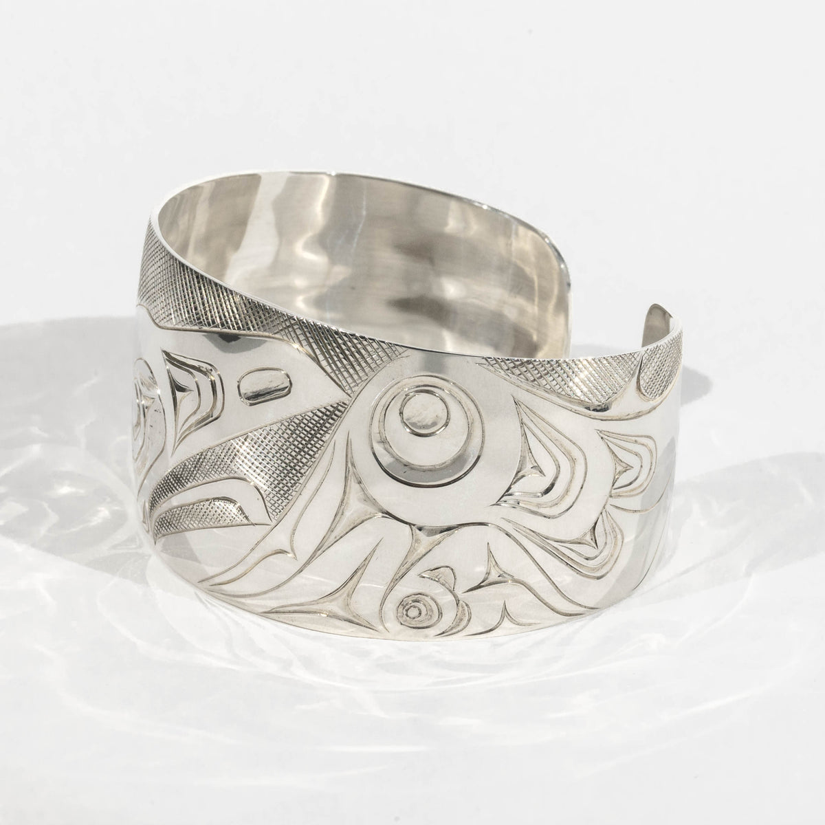 Right side of Sterling Silver Haida Raven bracelet with intricate formline designs showning the ravens wing hand carved by James Sayer Haida Jeweller on a white background