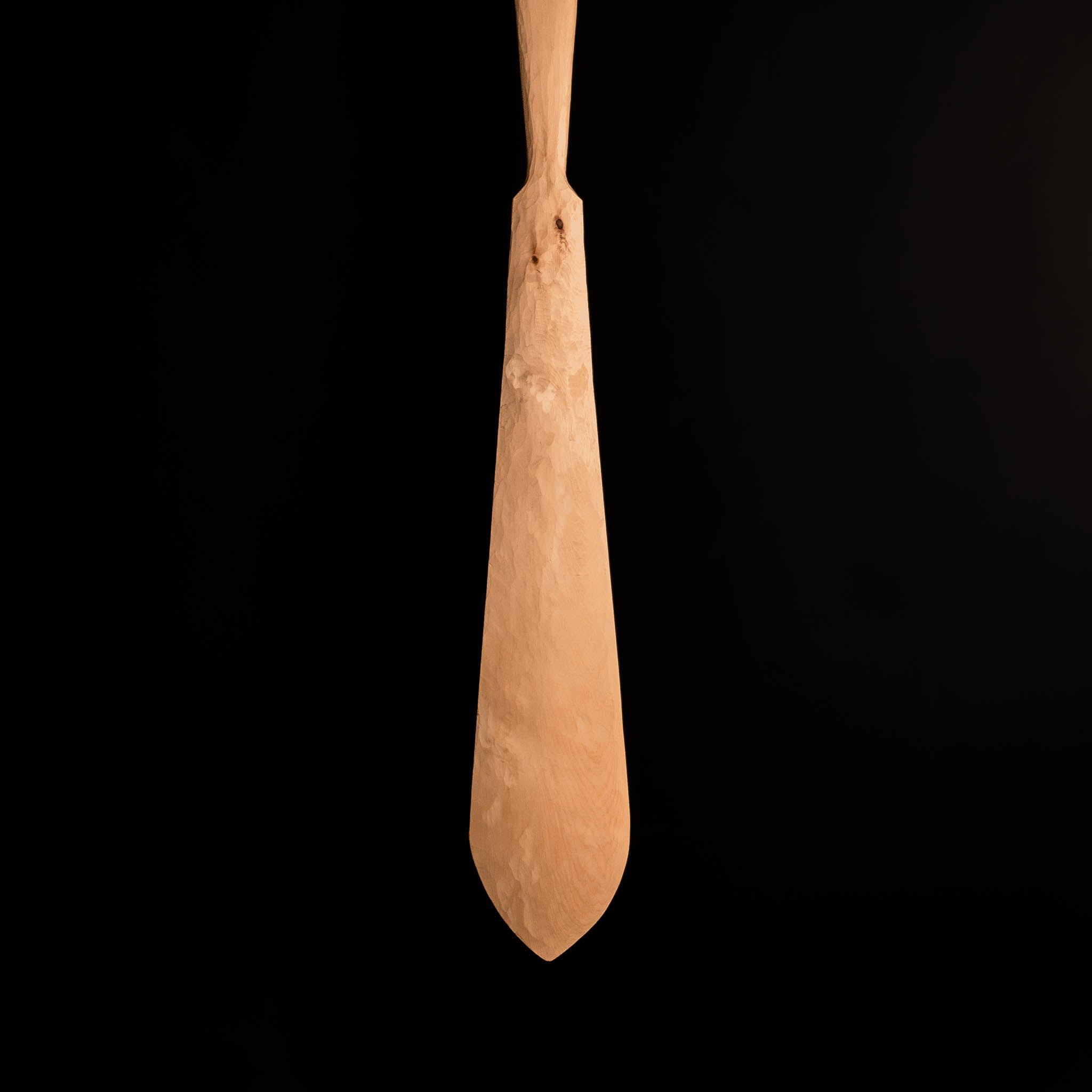 Wooden carved paddle on a black background.