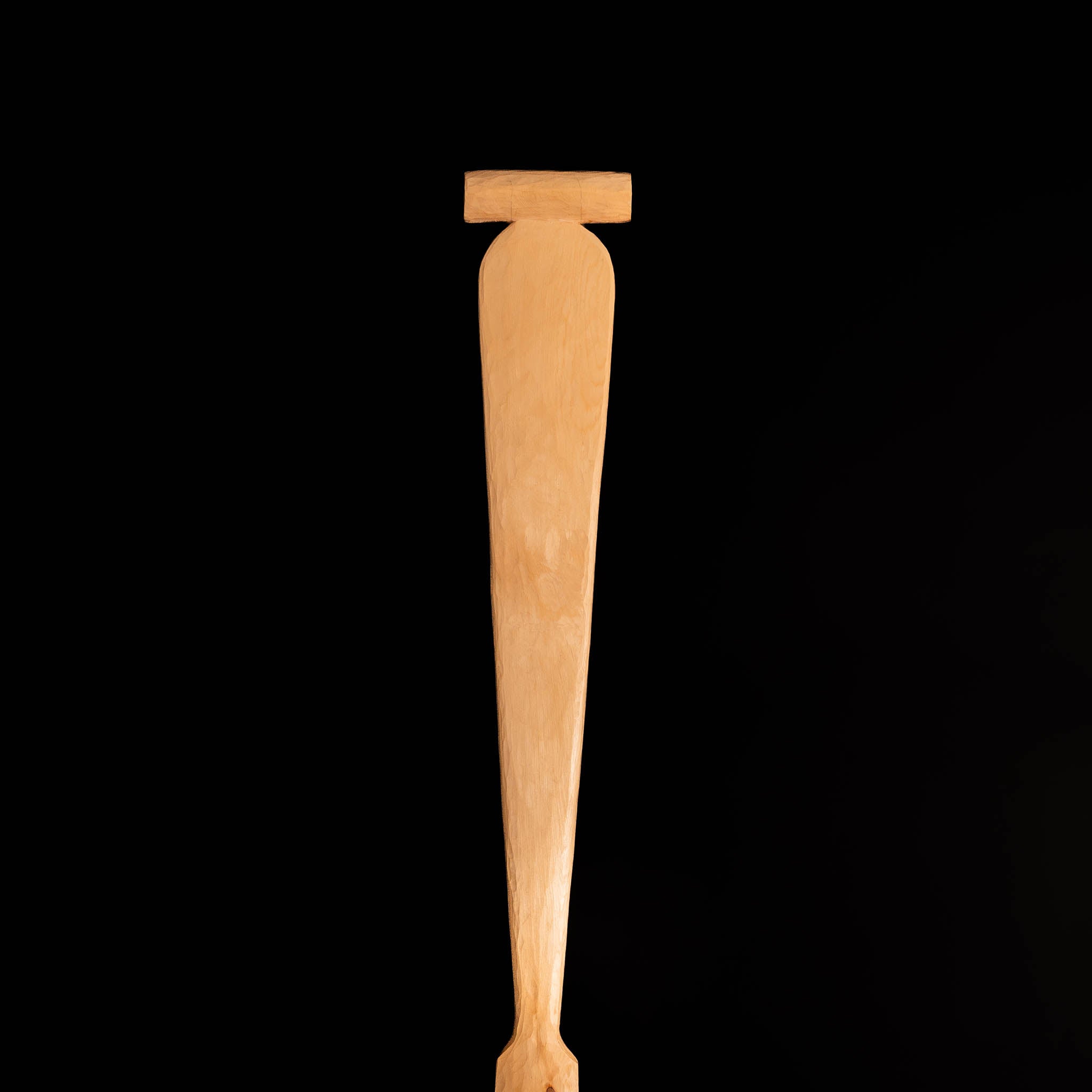 Wooden paddle handle a black background.