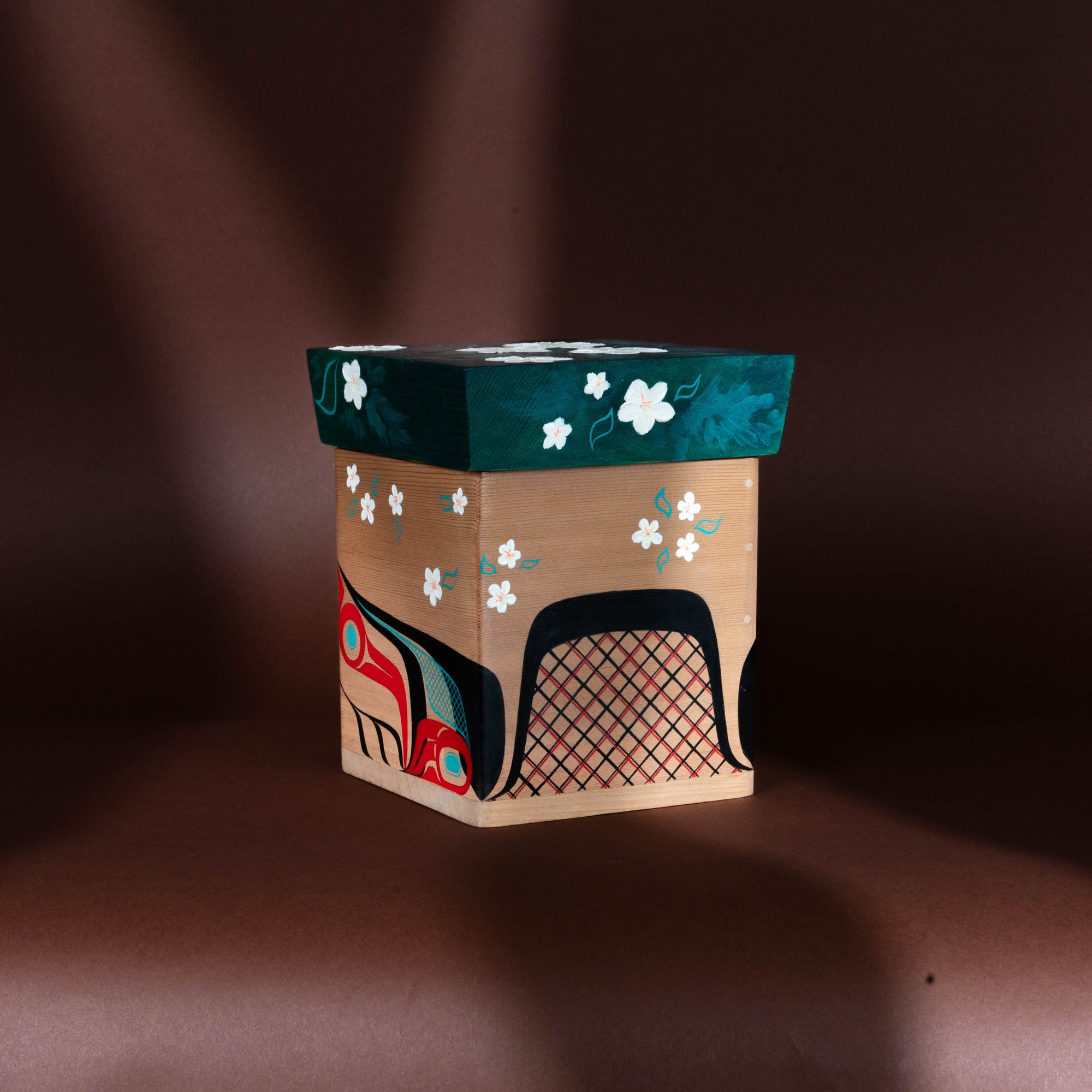 Decorative Haida Bentwood box with floral patterns and a colorful formline Beaver design on a brown background