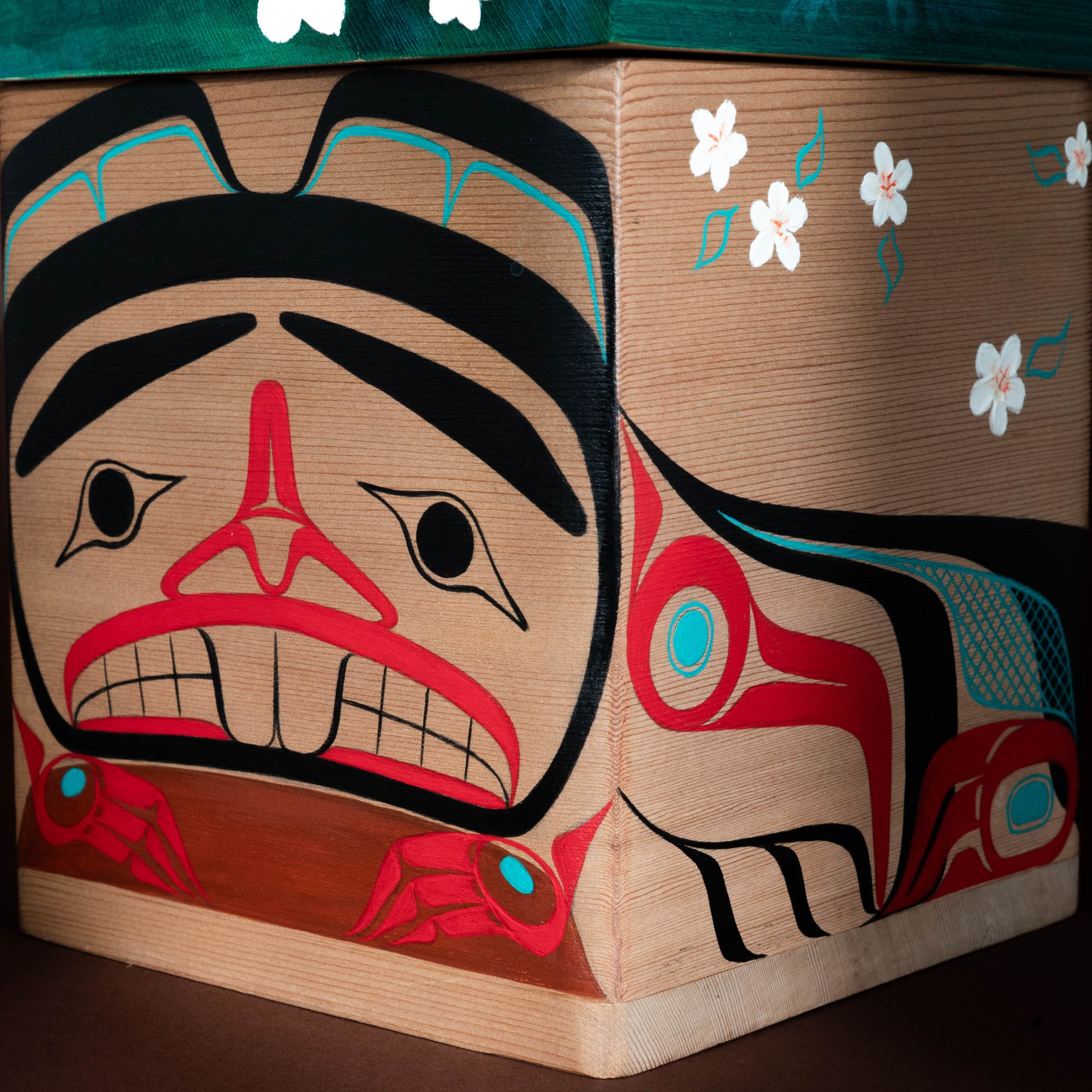 Wooden box with Native American design featuring red, black, and blue colors on a brown background.