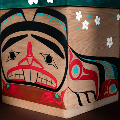 Wooden box with Native American design featuring red, black, and blue colors on a brown background.