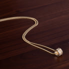 Close up of Gold salmon bone vertebrae on a gold chain by ts'mysen artist morgan asoyuf on a dark wooden surface 