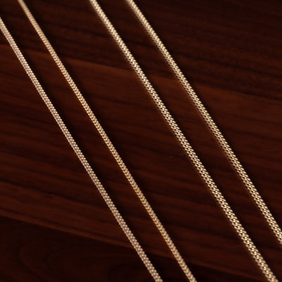 Close-up of gold chain on a dark brown background