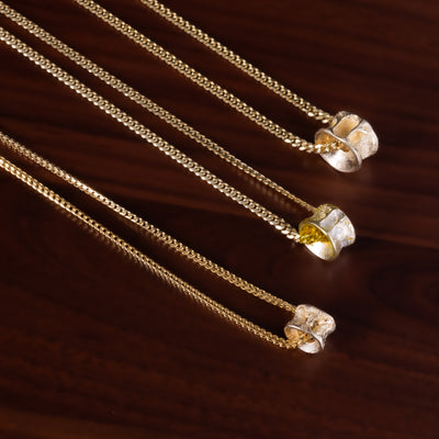 Three gold salmon bone vertebrae necklaces with on a brown textured background