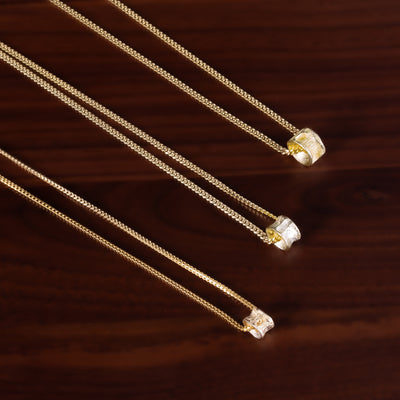 Three 10k gold salmon bone vertebrae necklaces with on a brown textured background