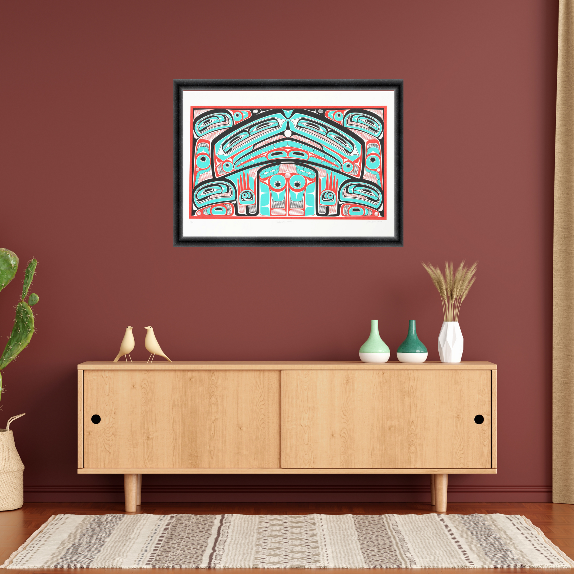 Framed abstract artwork on a red wall above a wooden cabinet with decorative items.