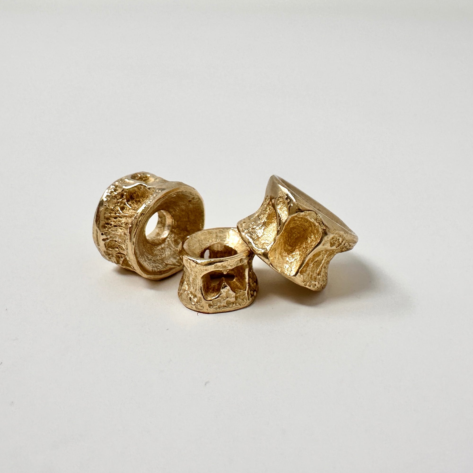 Three salmon bone gold charm castings on a white background.