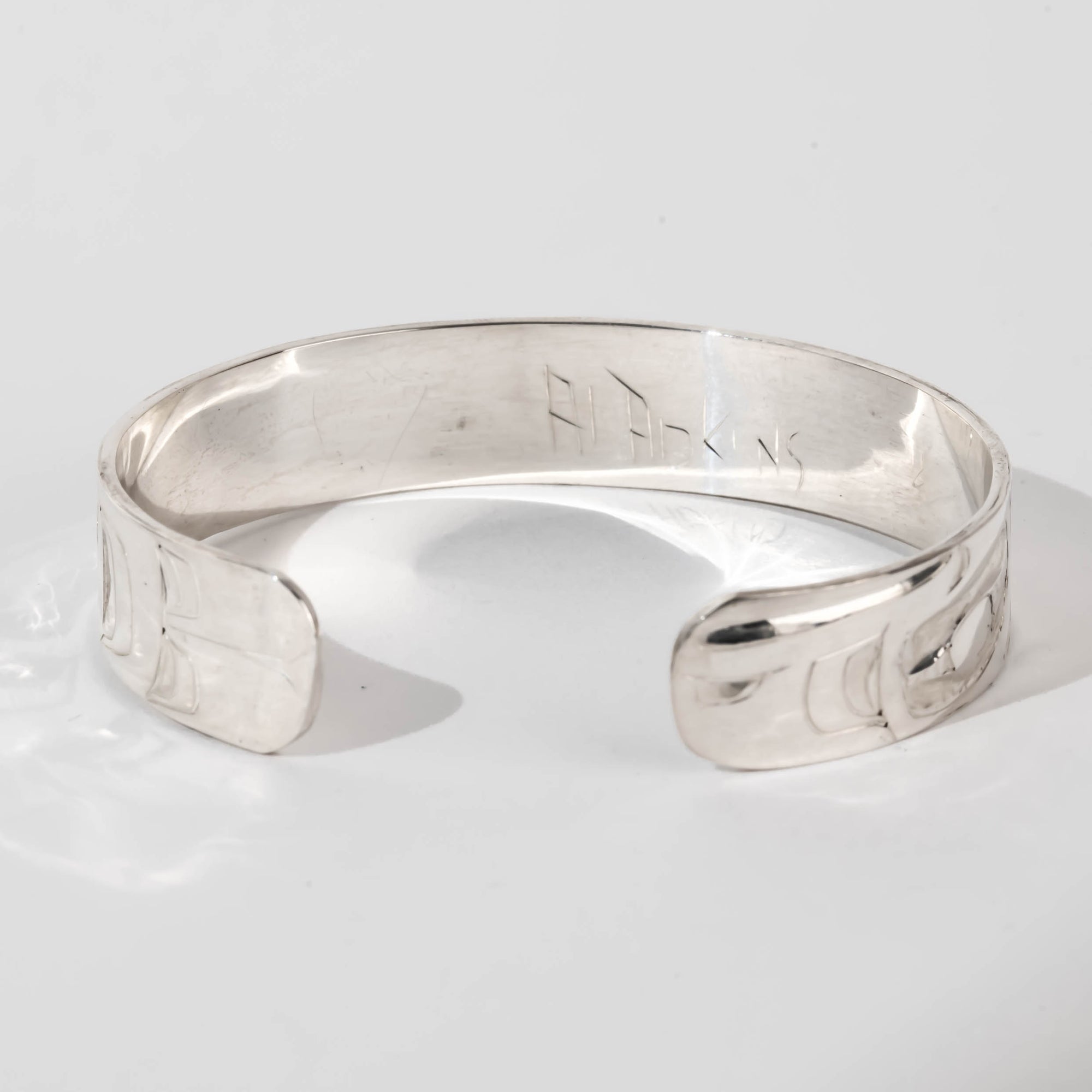 Hand carved sterling silver Raven bracelet by Haida artist Alvin Adkins back view showing original signature