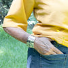 Alvin Adkins hummingbird bracelet worn by model in yellow holding a butter cup with the Tlell river and forest behind her