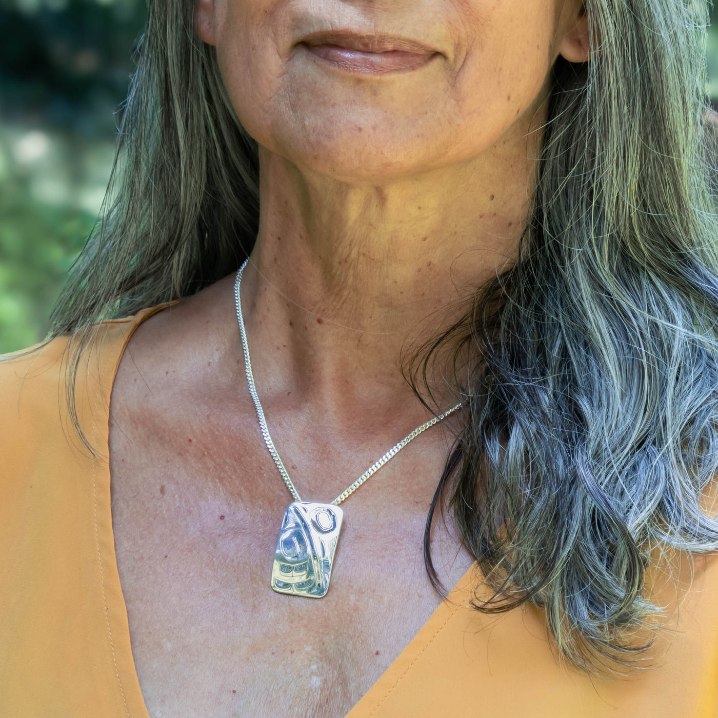 Woman wearing a necklace with a pendant outdoors