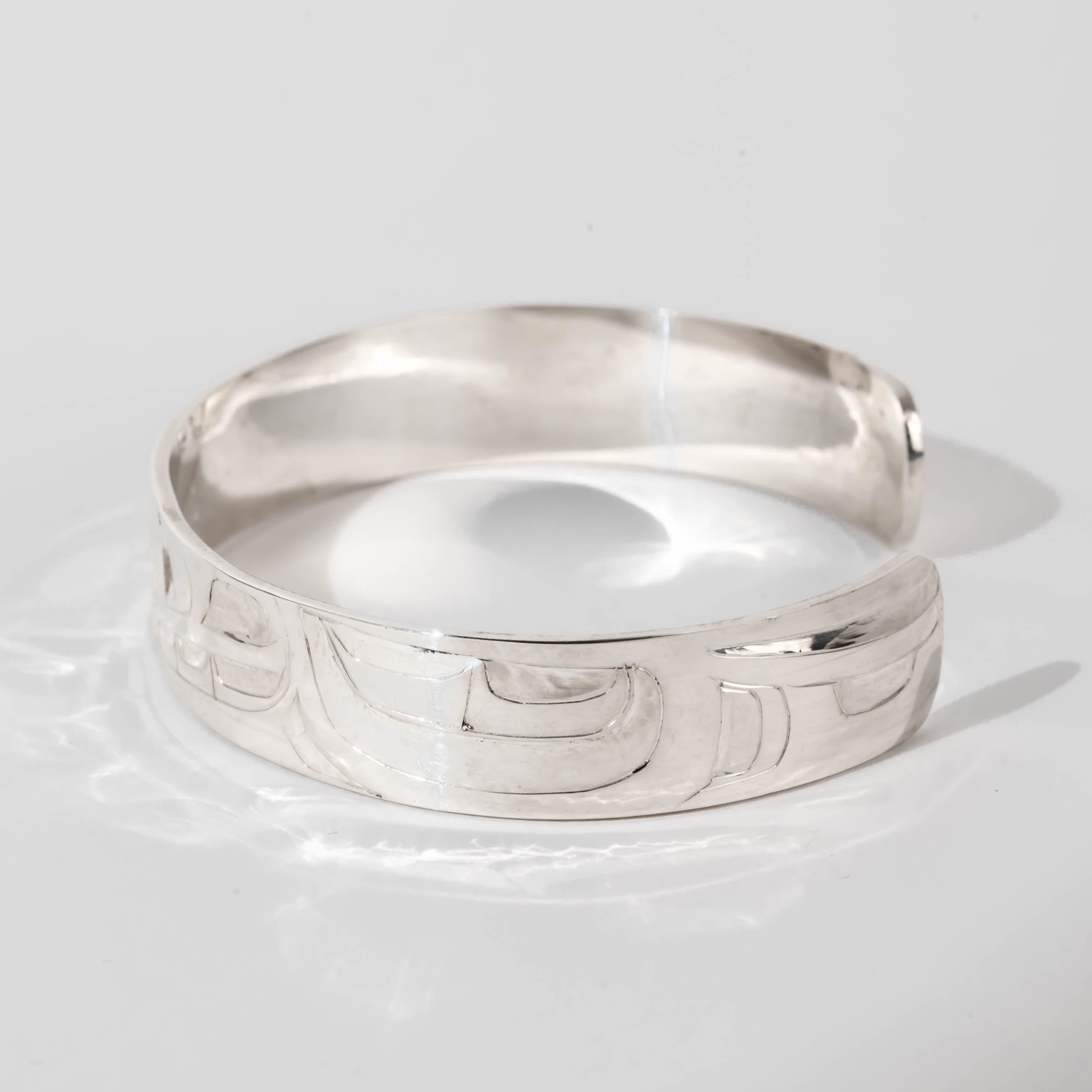 Hand carved sterling silver Orca bracelet by Haida artist Alvin Adkins side view
