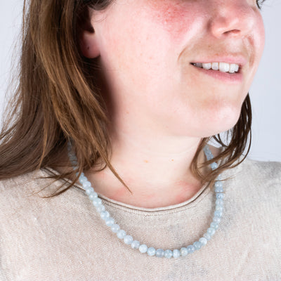 Locally made blue topaz hand beaded necklace worn by model close up