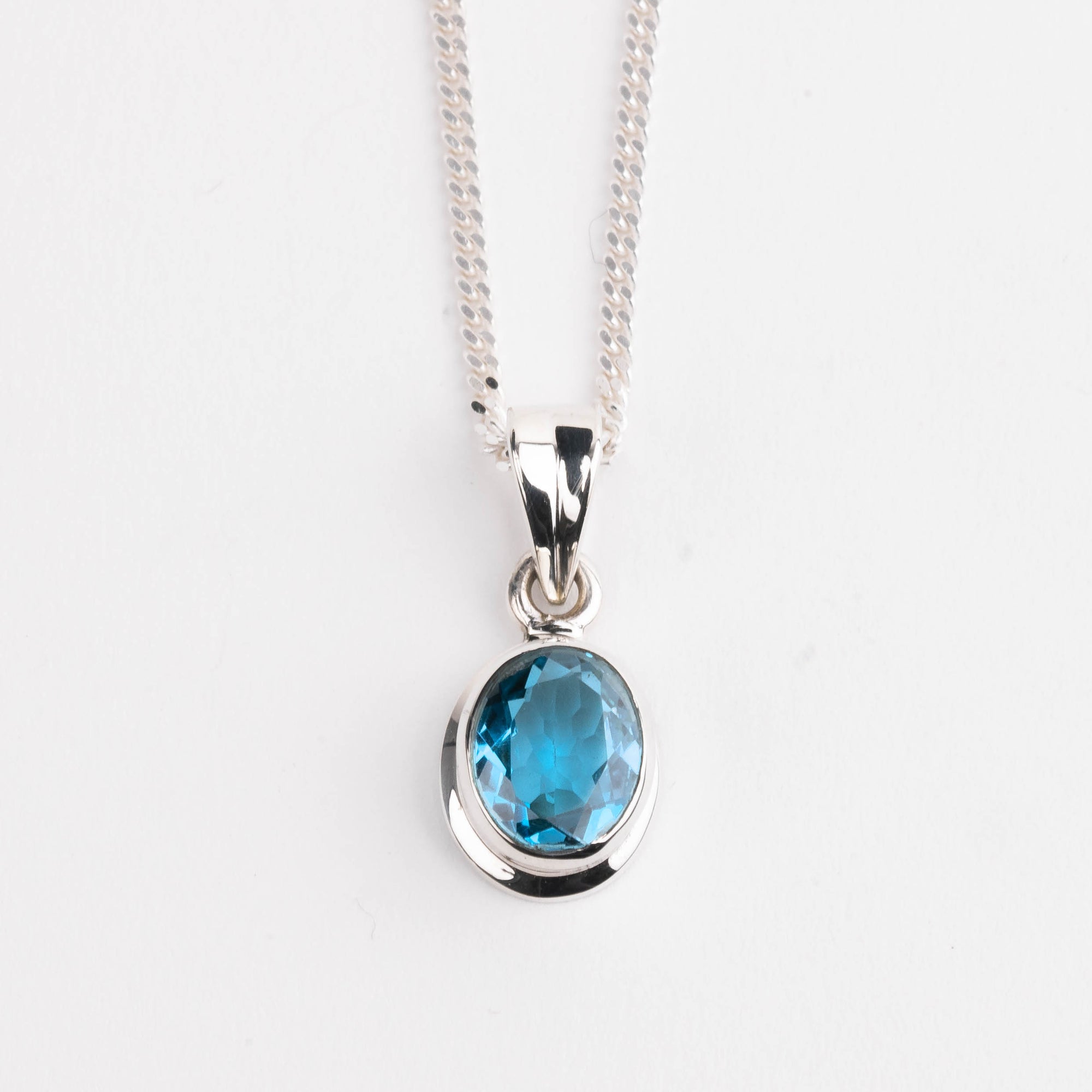 Silver necklace with a blue gemstone pendant on a white background