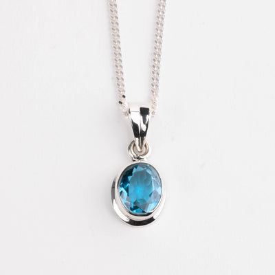 Silver necklace with a blue gemstone pendant on a white background