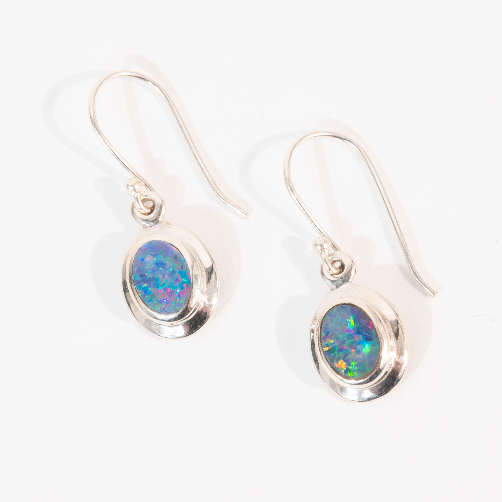Pair of silver earrings with opal stones on a white background