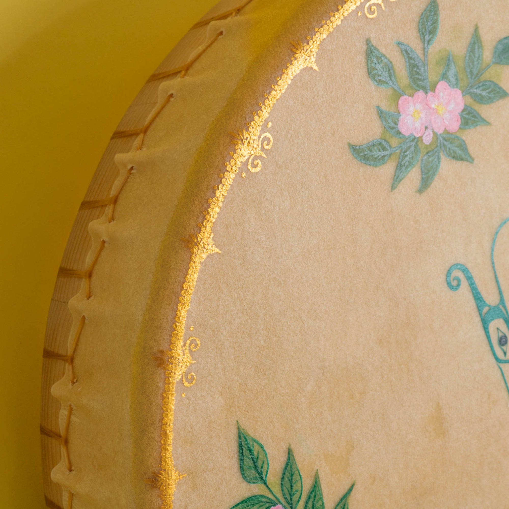 Close up of corner of drum with shiny gold paint and flowers.