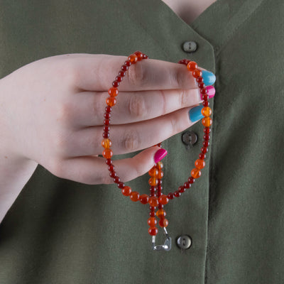 Photo showing of the beads of a Hand beaded deep red and orange Carnelian Agate Necklace with  sterling silver clasp held by model
