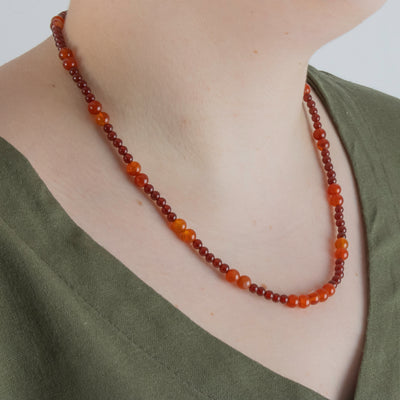Photo showing of the beads of a Hand beaded deep red and orange Carnelian Agate Necklace with  sterling silver clasp on a model