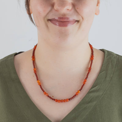 Photo showing of the beads of a Hand beaded deep red and orange Carnelian Agate Necklace with  sterling silver clasp on a model