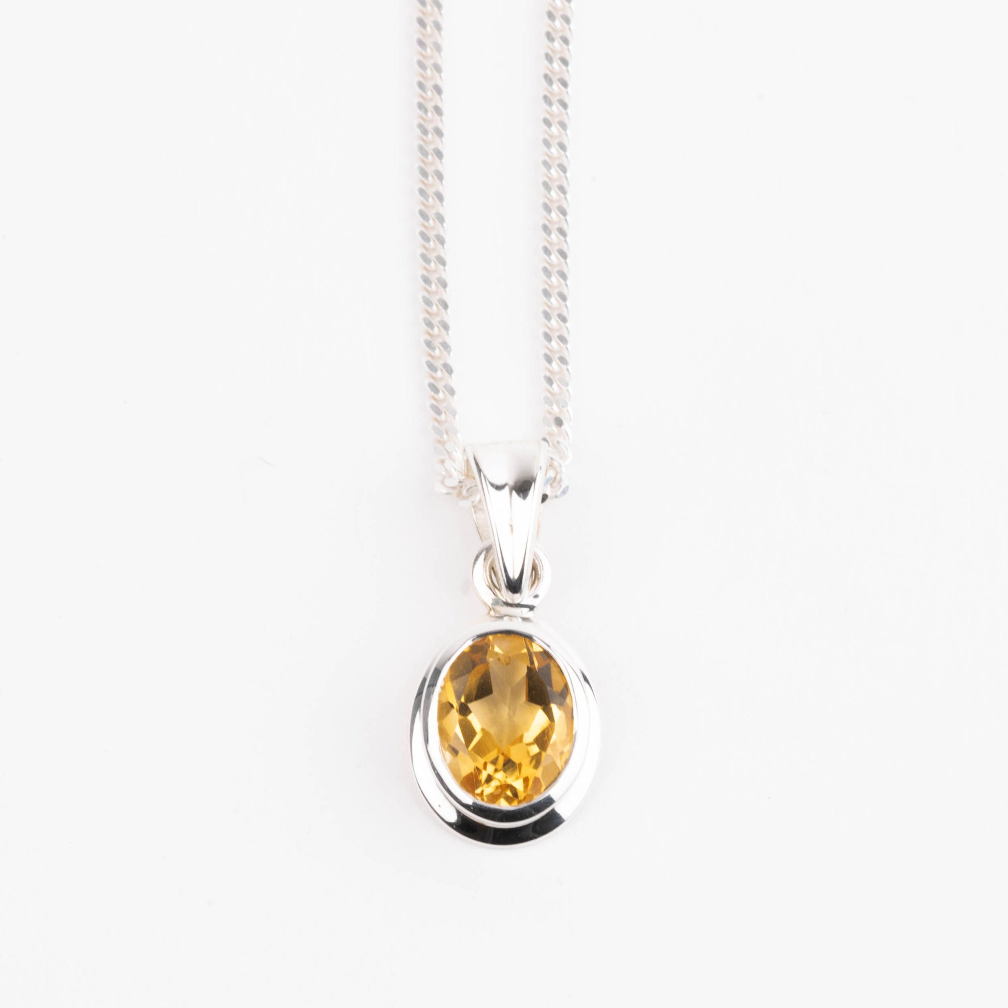 Silver pendant with a yellow citrine gemstone on a white background