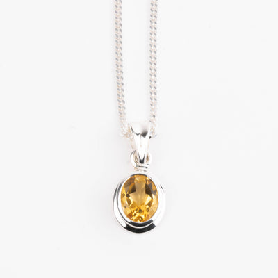 Silver pendant with a yellow citrine gemstone on a white background