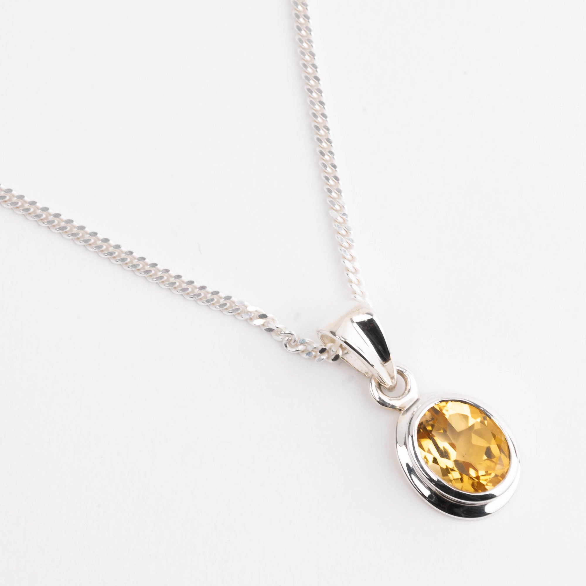 Silver necklace with a yellow citrine gemstone pendant on a white background