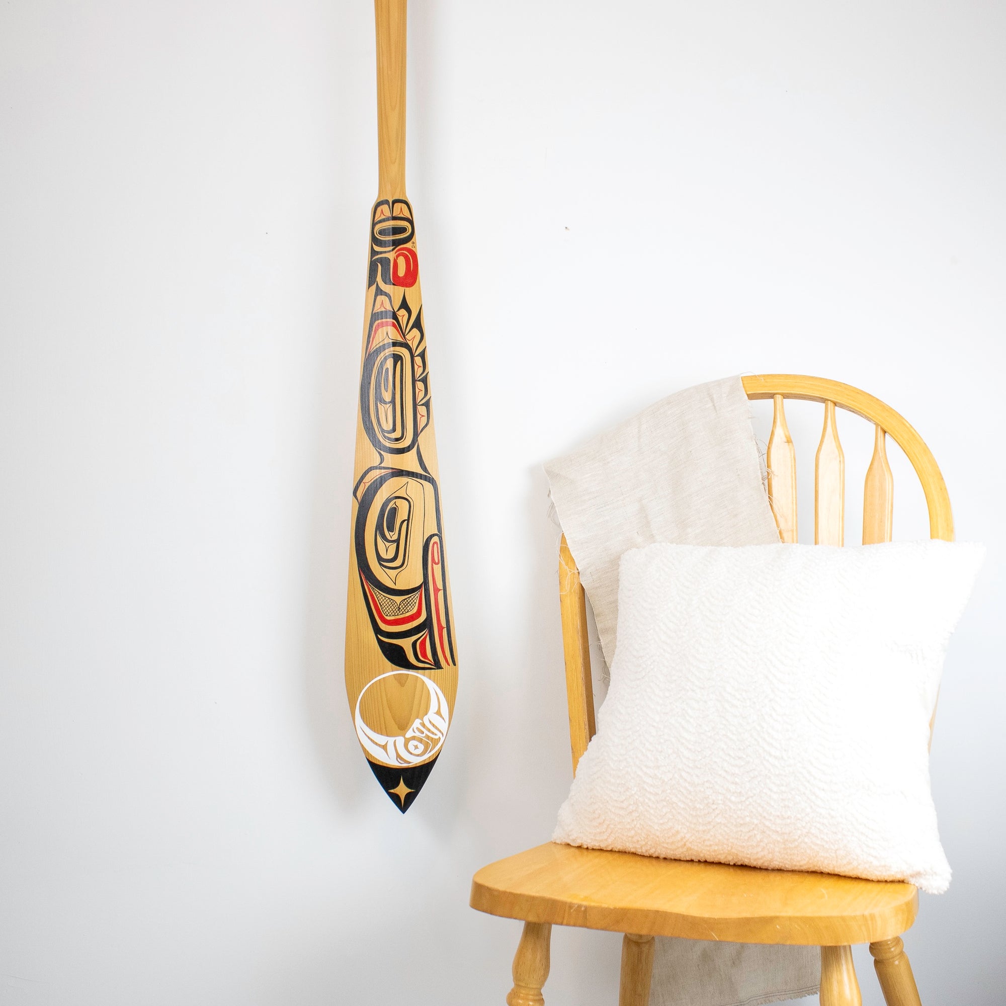 Part of wood paddle beside a chair and pillow