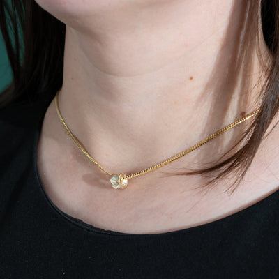 Gold necklace with a small 10k Gold Salmon bone Vertebrae pendant worn by a person against a black background