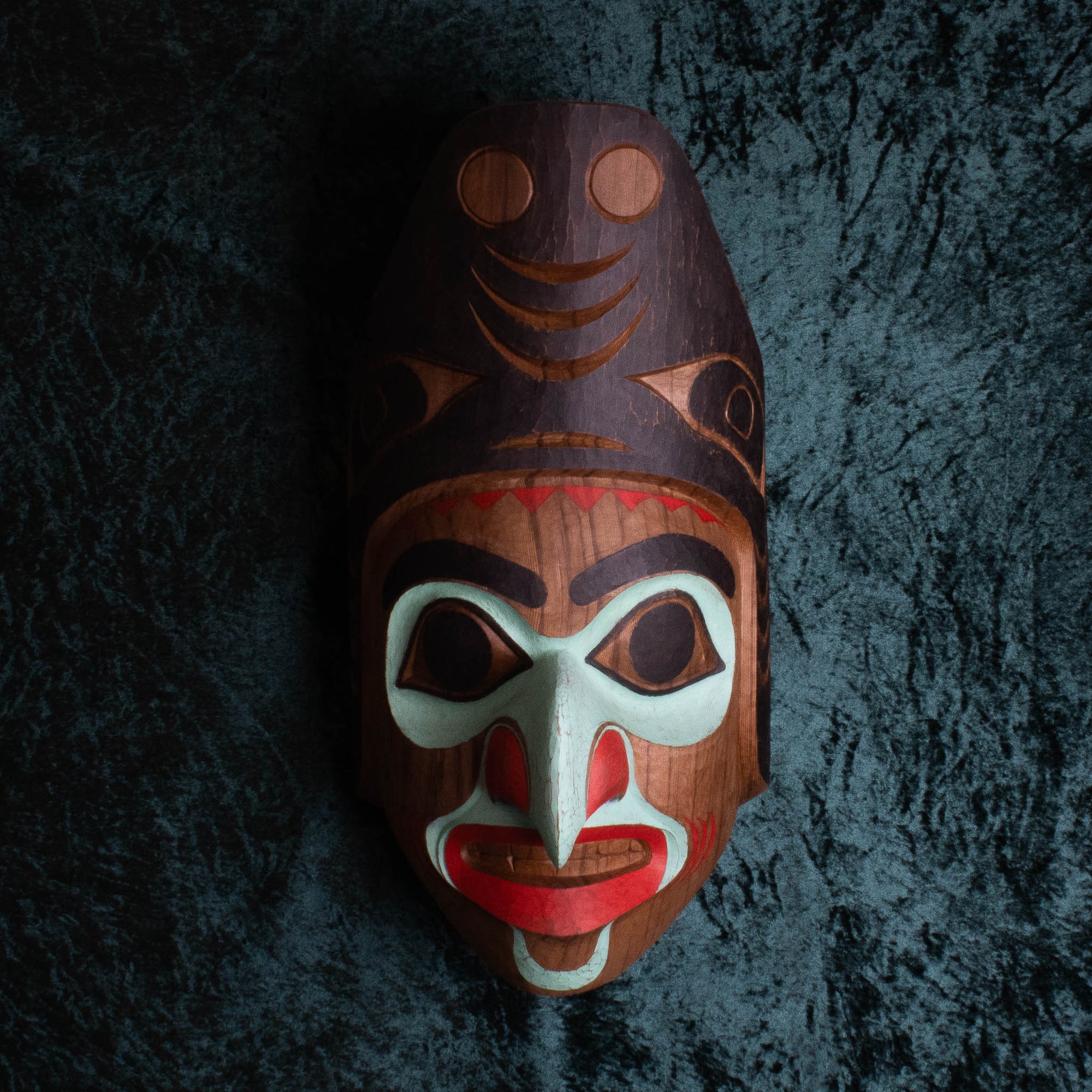 Carved wooden northwest coast mask with green background