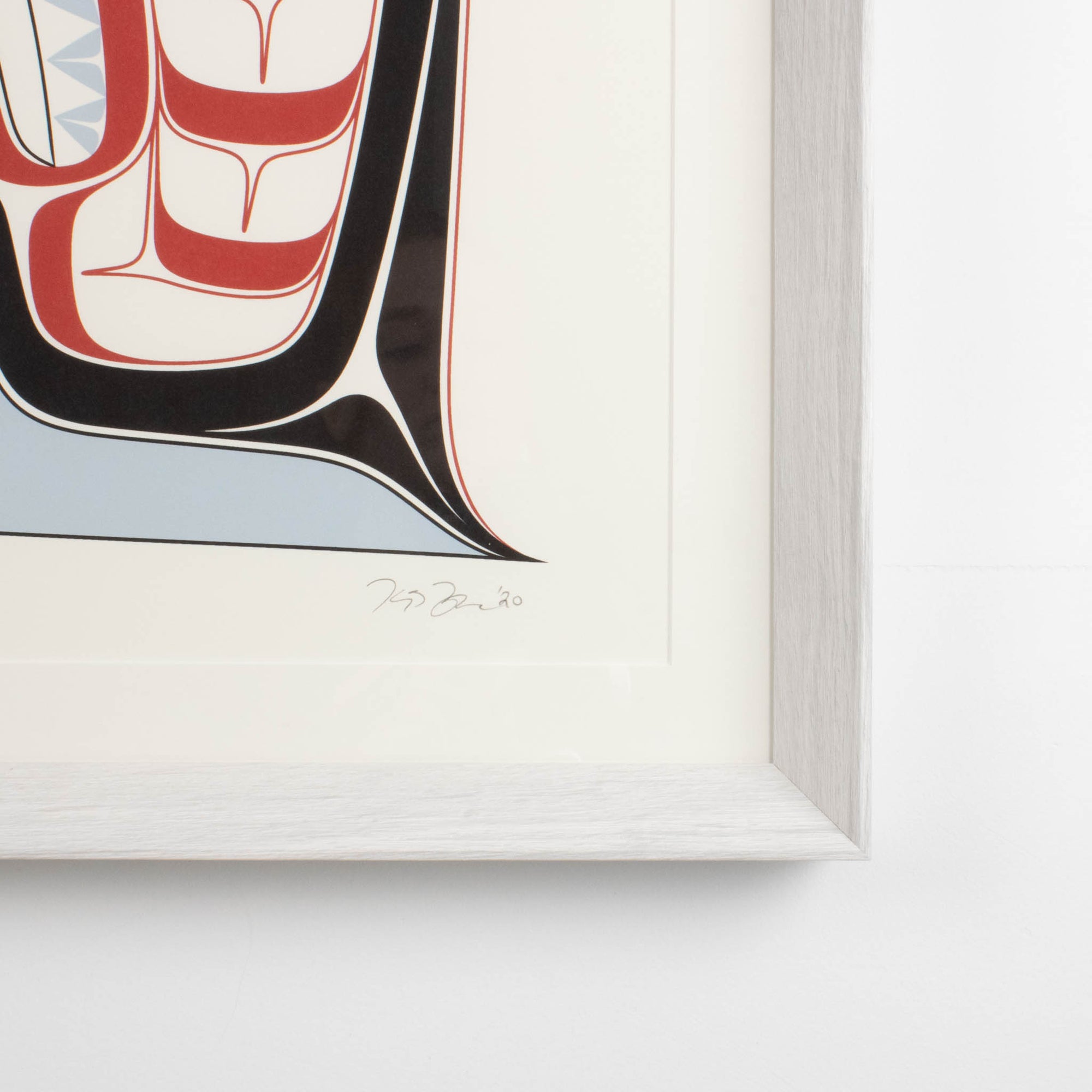 Haida Art print featuring supernatural being Dogfish mother. Framed in a driftwood was frame. In an interior design. Showing the corner of the frame and the artists original signature and date.