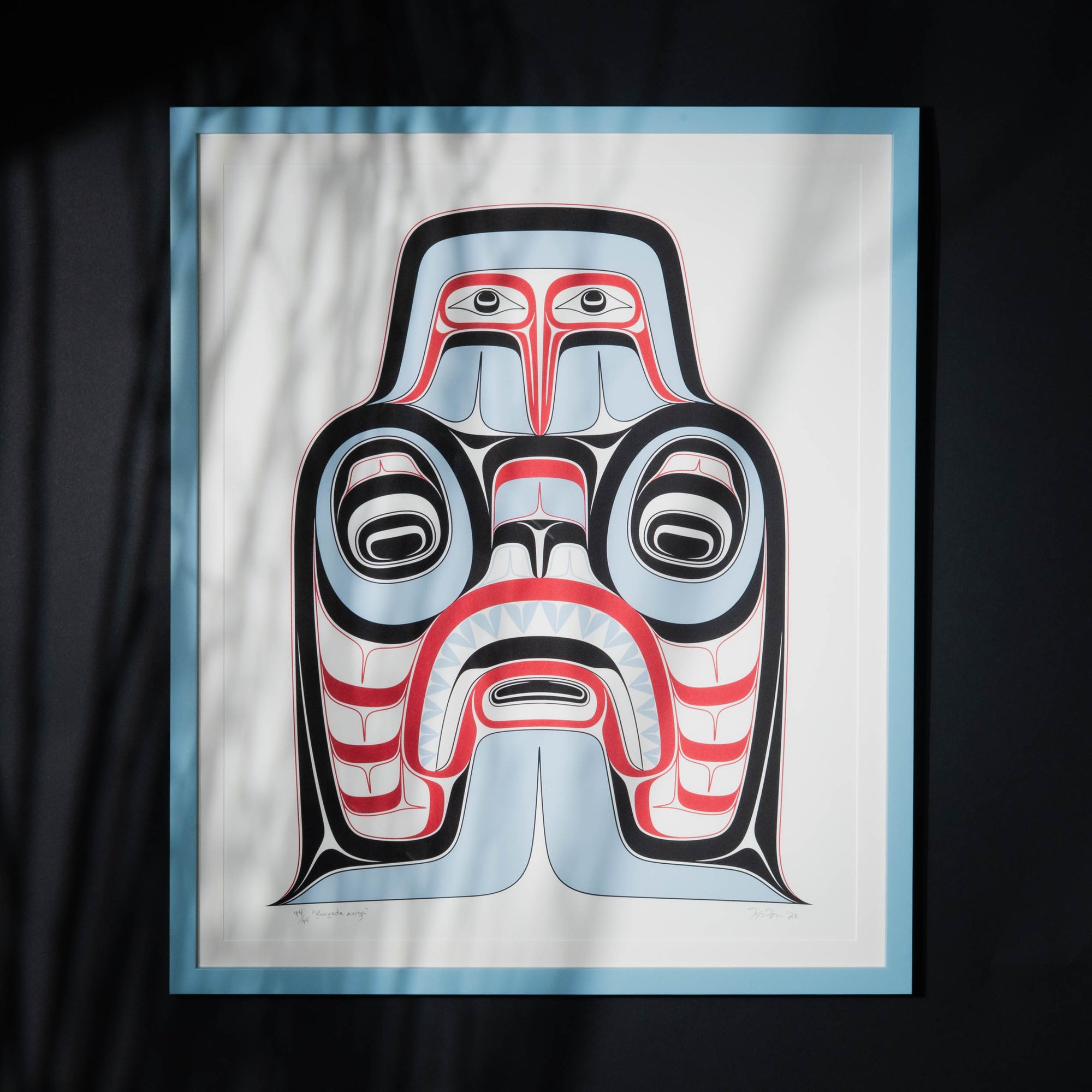 Haida Art print featuring supernatural being Dogfish mother. with bold red and black, and soft blue hues to show contrast, framed in a driftwood was frame with a shadowy light