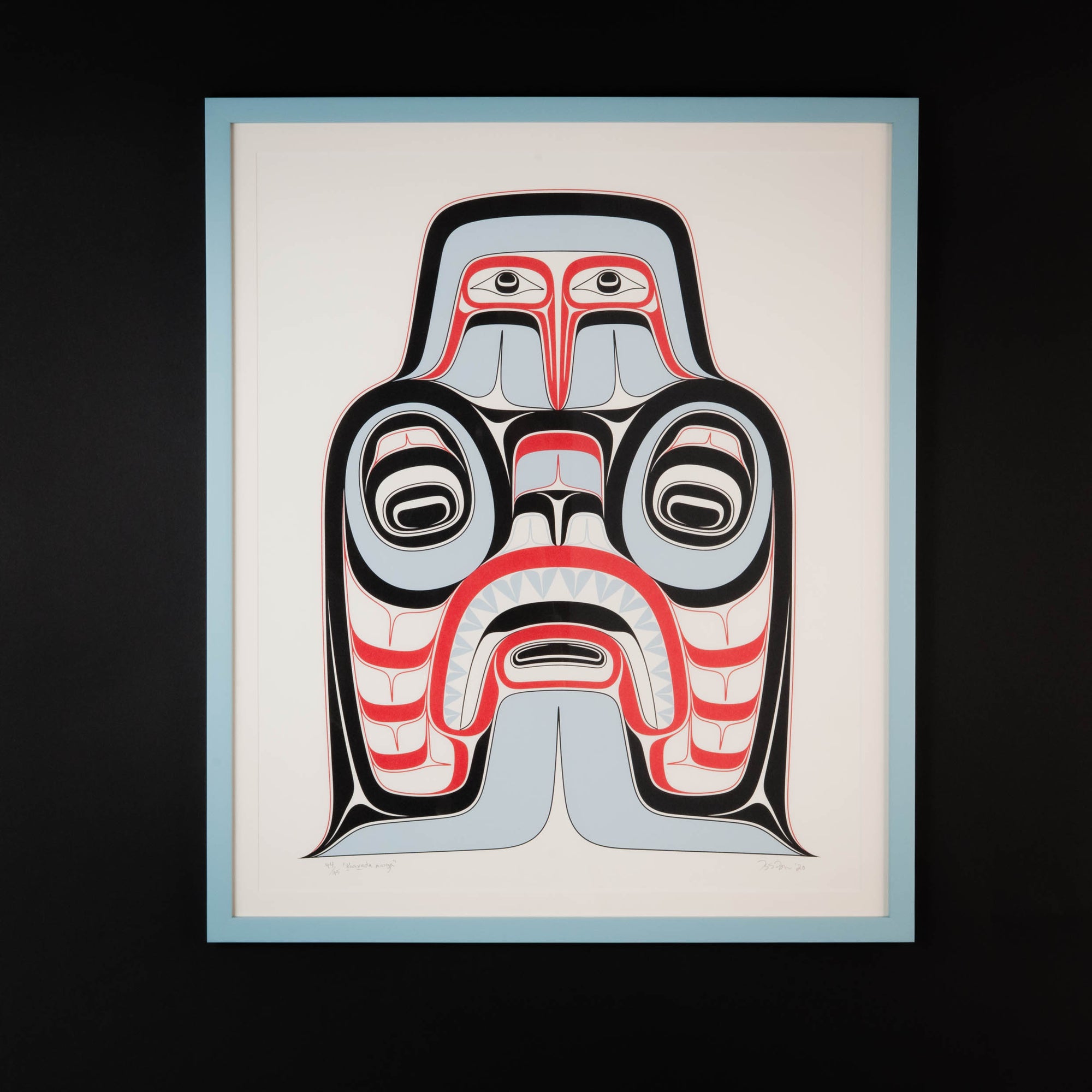 Framed artwork of a stylized Haida Art print featuring supernatural being Dogfish mother. with bold red and black, and soft blue hues to show contrast, framed in a driftwood was frame on a light background.