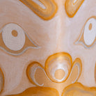 Abstract close-up of artwork with stylized eye-like shapes and flowing organic forms in warm cream, tan, orange, and white tones.