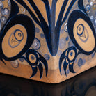 Close-up of a handcrafted wooden box with intricate hand-painted designs in dark blue and natural wood tones.