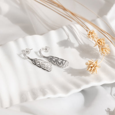 Sterling Silver Eagle Manifesto earrings on a white serving dish with dried flowers on a what background