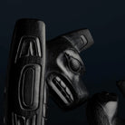 Thunderbird carved in a black glossy stone with formline patterns on a dark background.