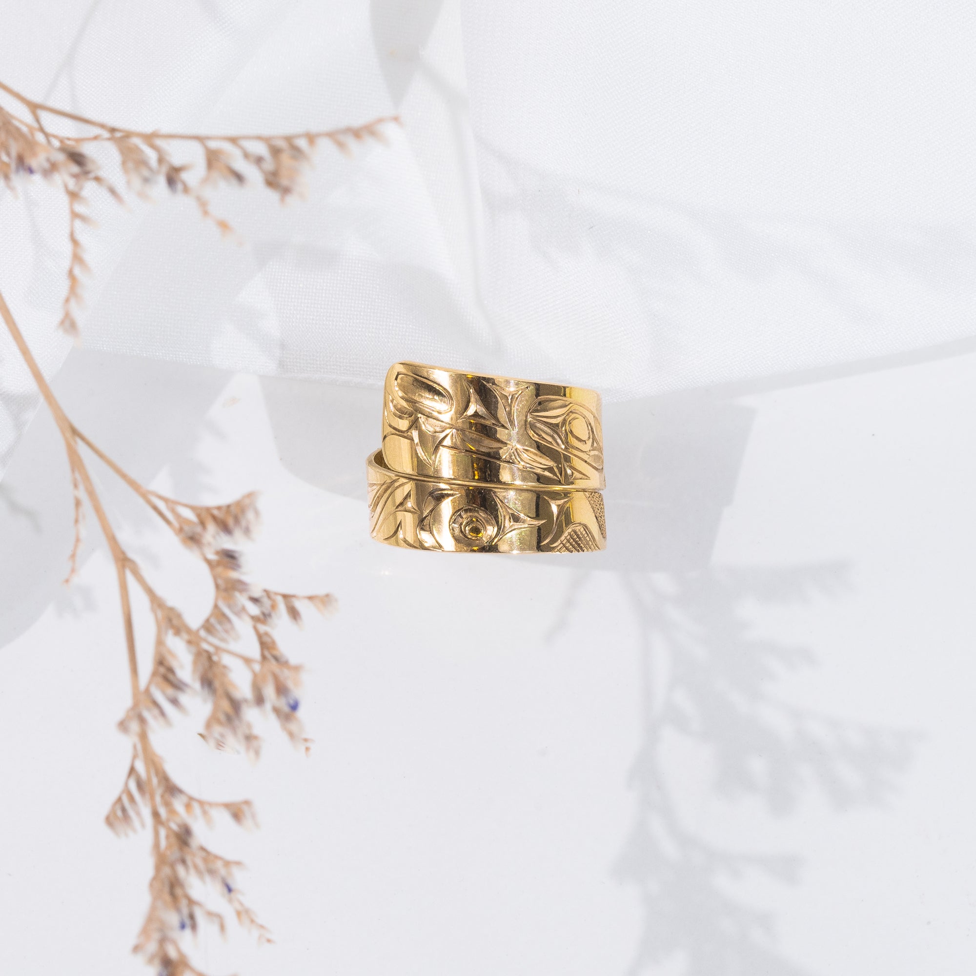 14k Gold wrap ring with intricate formline wolf design hand carved by Haida artist James Sawyer on a light background