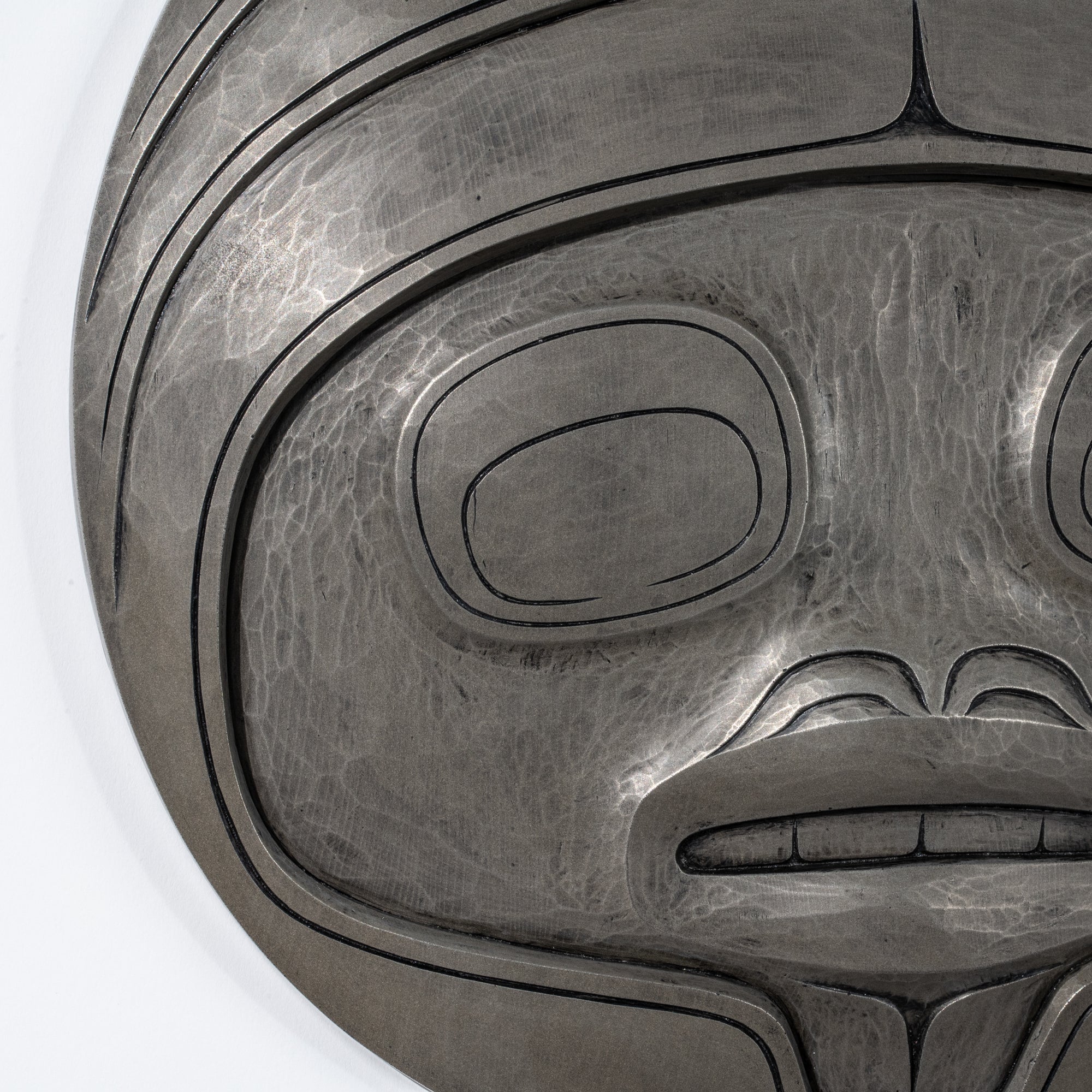 Close-up of a metallic looking Fungus Man Mask Casting mask with intricate designs by Haida artist Cori Savard on a white back ground on a white background