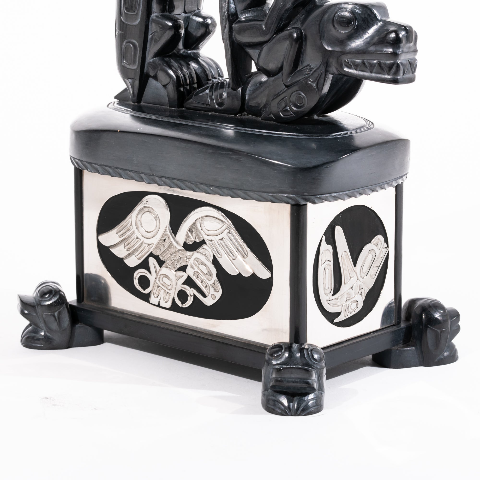 Haida argillite killer whale and thunderbird argillite and sterling silver box done by master Haida artist Ding Hutchingson on a white background showing close up of the silver carving