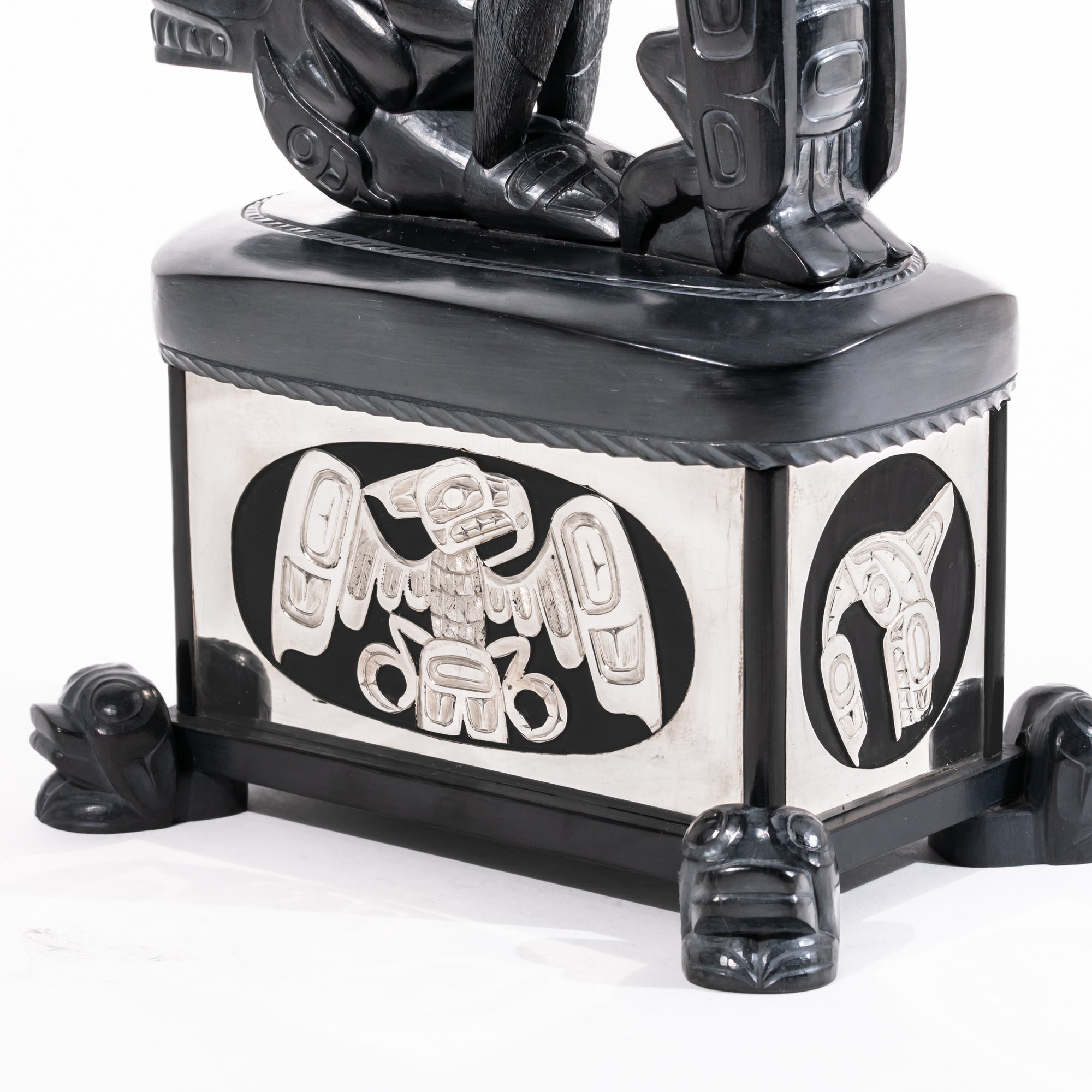 Haida argillite killer whale and thunderbird argillite and sterling silver box done by master Haida artist Ding Hutchingson on a white background showing close up of the silver thunderbird