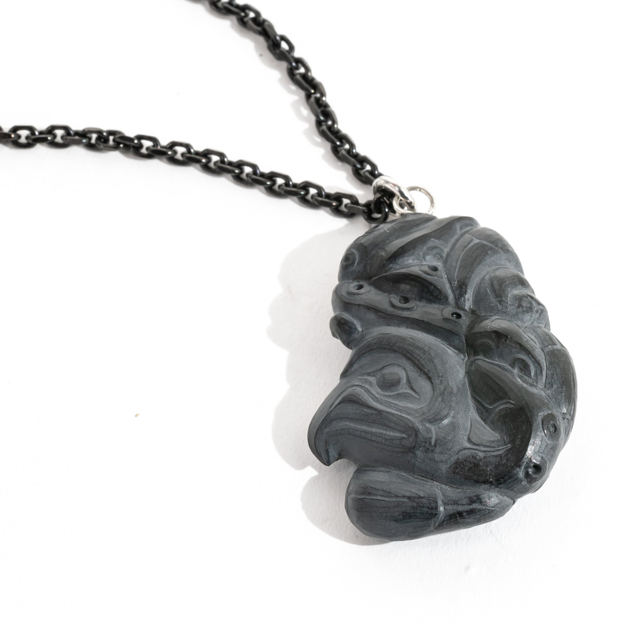 Close up of Black Argillite Octopus pendant necklace with intricate Haida Carvings on a white background made by Local Haida Gwaii Artist Melanie Russ