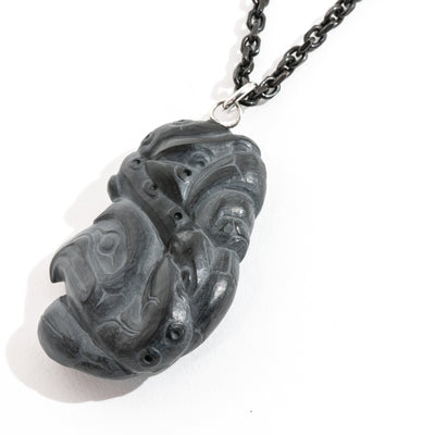 Close up of tentacles wrapping around both sides of Black Argillite Octopus pendant necklace with intricate Haida Carvings on a white background made by Local Haida Gwaii Artist Melanie Russ