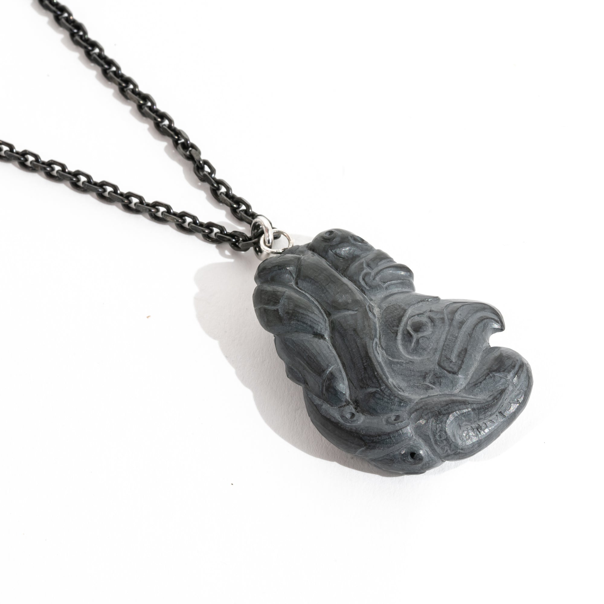 Left side of Black Argillite Octopus pendant necklace with intricate Haida Carvings on a white background made by Local Haida Gwaii Artist Melanie Russ