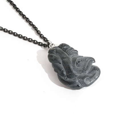 Left side of Black Argillite Octopus pendant necklace with intricate Haida Carvings on a white background made by Local Haida Gwaii Artist Melanie Russ