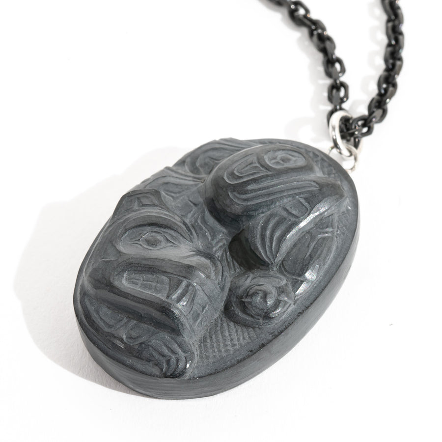 Close up of Right side of Black Argillite Sea Bear pendant necklace with intricate Haida Carvings on a white background made by Local Haida Gwaii Artist Melanie Russ