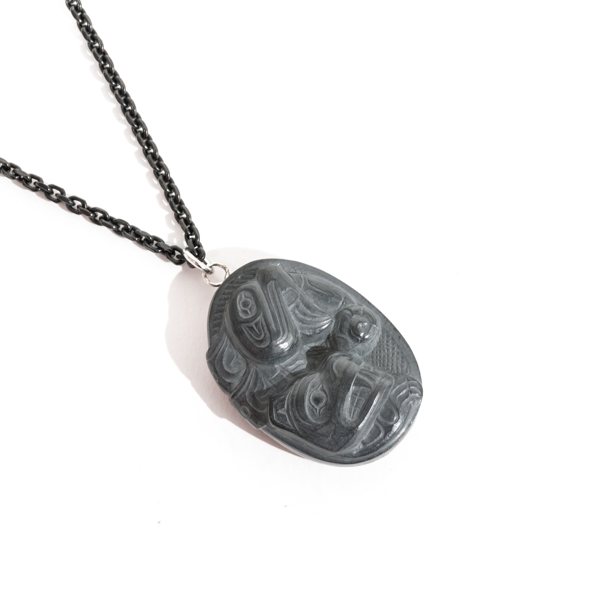 Black Argillite Sea Bear pendant necklace with intricate Haida Carvings on a white background made by Local Haida Gwaii Artist Melanie Russ