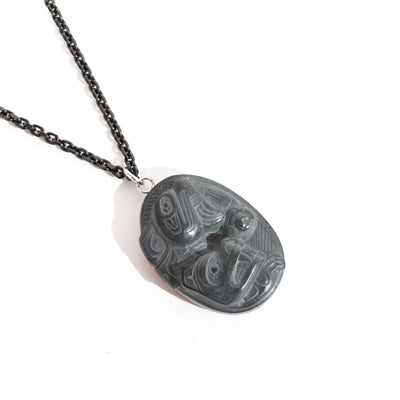 Black Argillite Sea Bear pendant necklace with intricate Haida Carvings on a white background made by Local Haida Gwaii Artist Melanie Russ